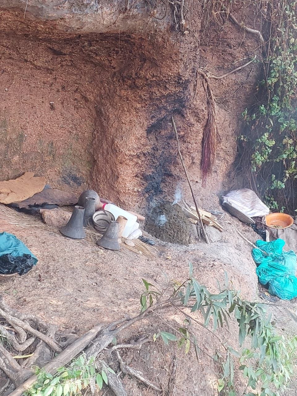 Clay pots, brooms and smouldering embers at a rock shrine used for reconciliation work
